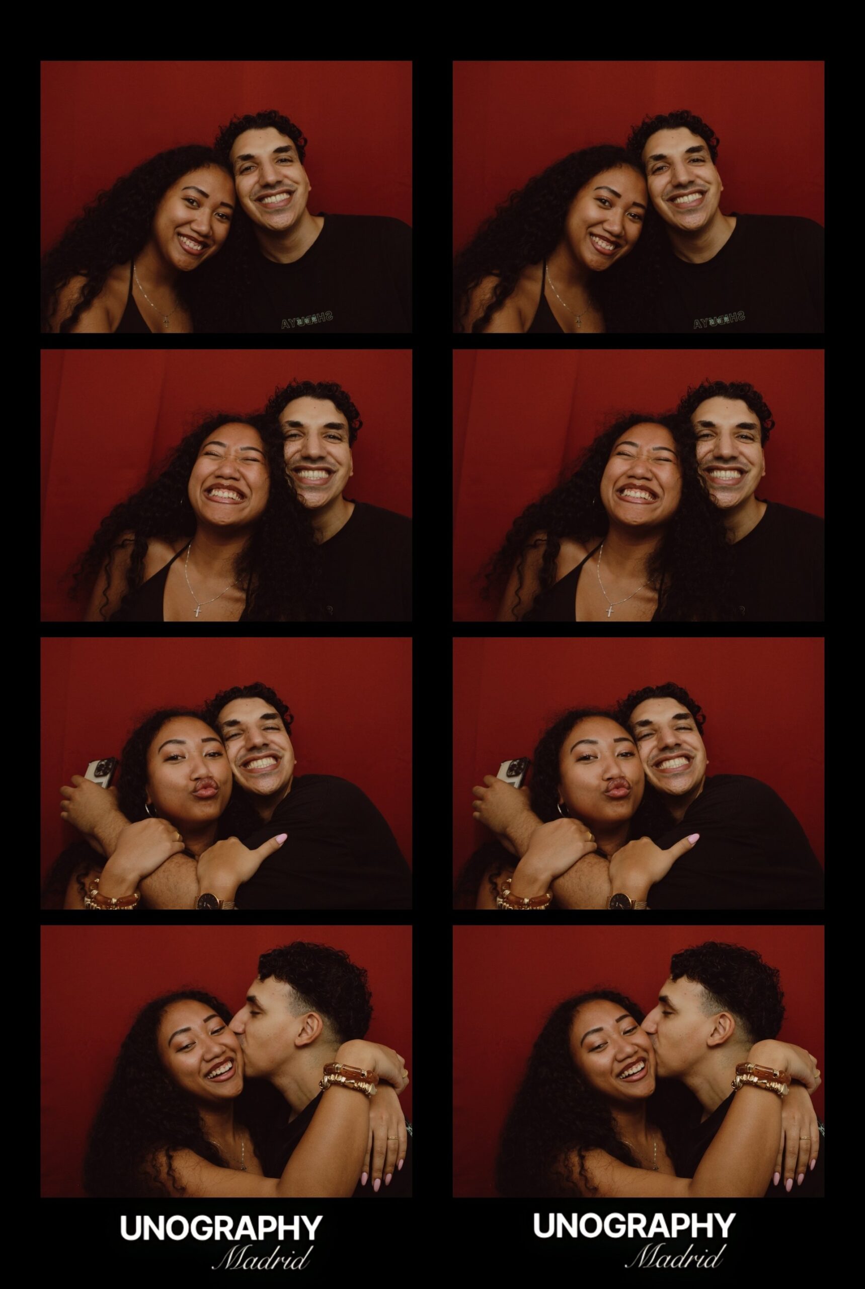 Couple posing in the classic photobooth at Unography Madrid, printed photo strips with a red background